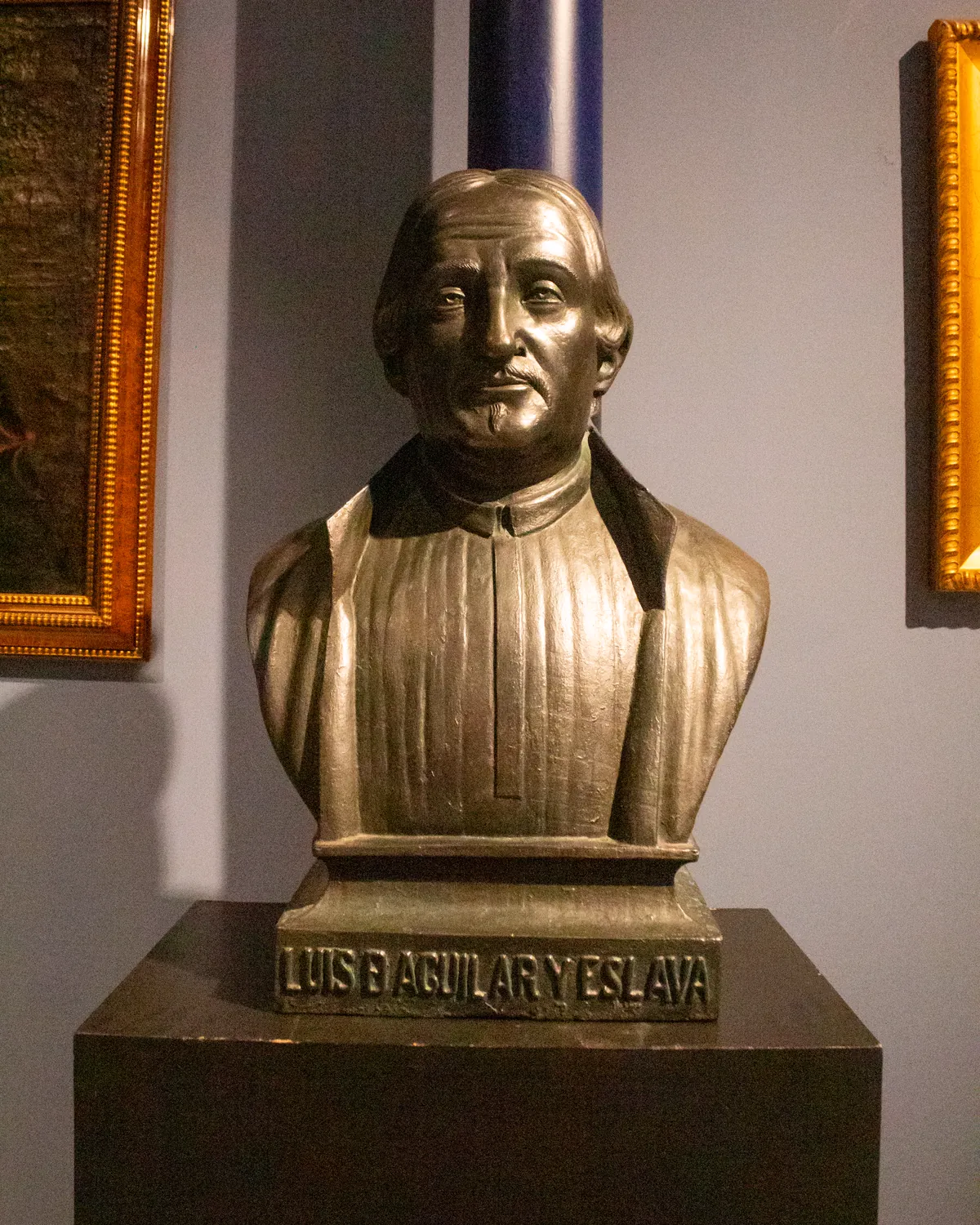 Busto del fundador sobre un pedestal con su nombre grabado, «Luis D. Aguilar y Eslava», entre dos cuadros con marco dorado