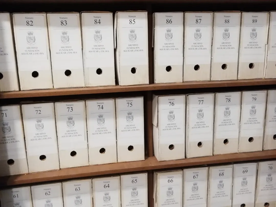 Estanterías con cajas de archivo blancas, numeradas del 61 al 89, con el escudo de la Fundación y el rótulo «Archivo Fundación Aguilar y Eslava»