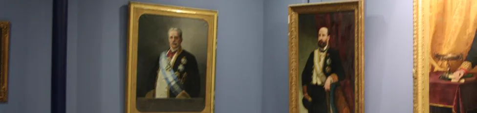 Retratos al óleo de directores con marco dorado en una sala de paredes azules